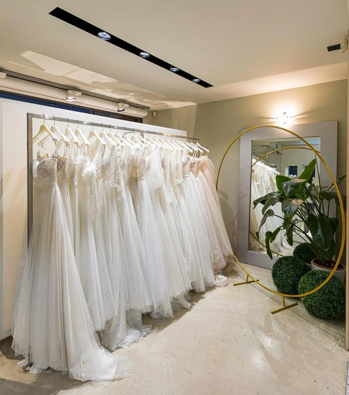 Abiti da sposa appesi accanto a uno specchio ovale.