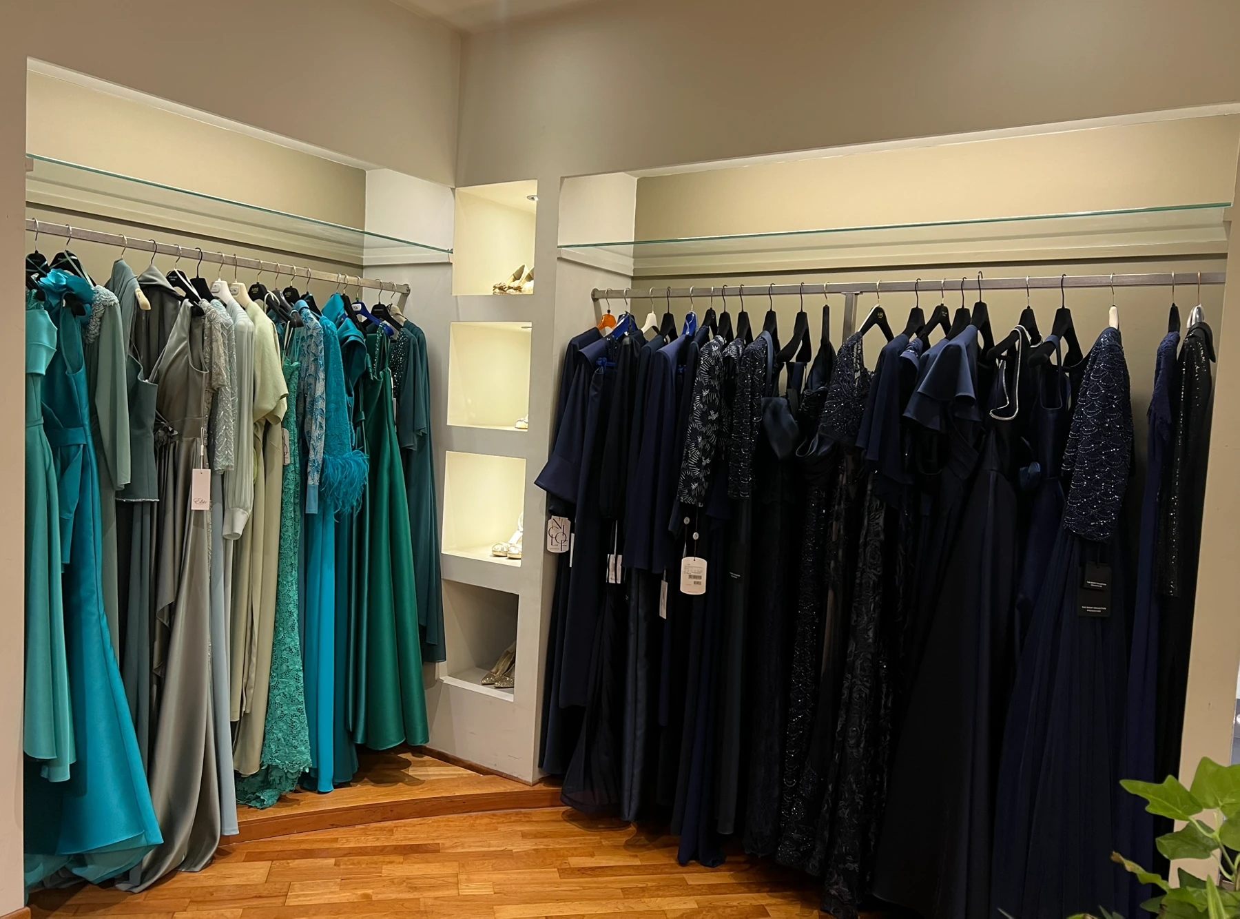 Abiti da cerimonia nei toni del verde e del blu esposti in boutique.