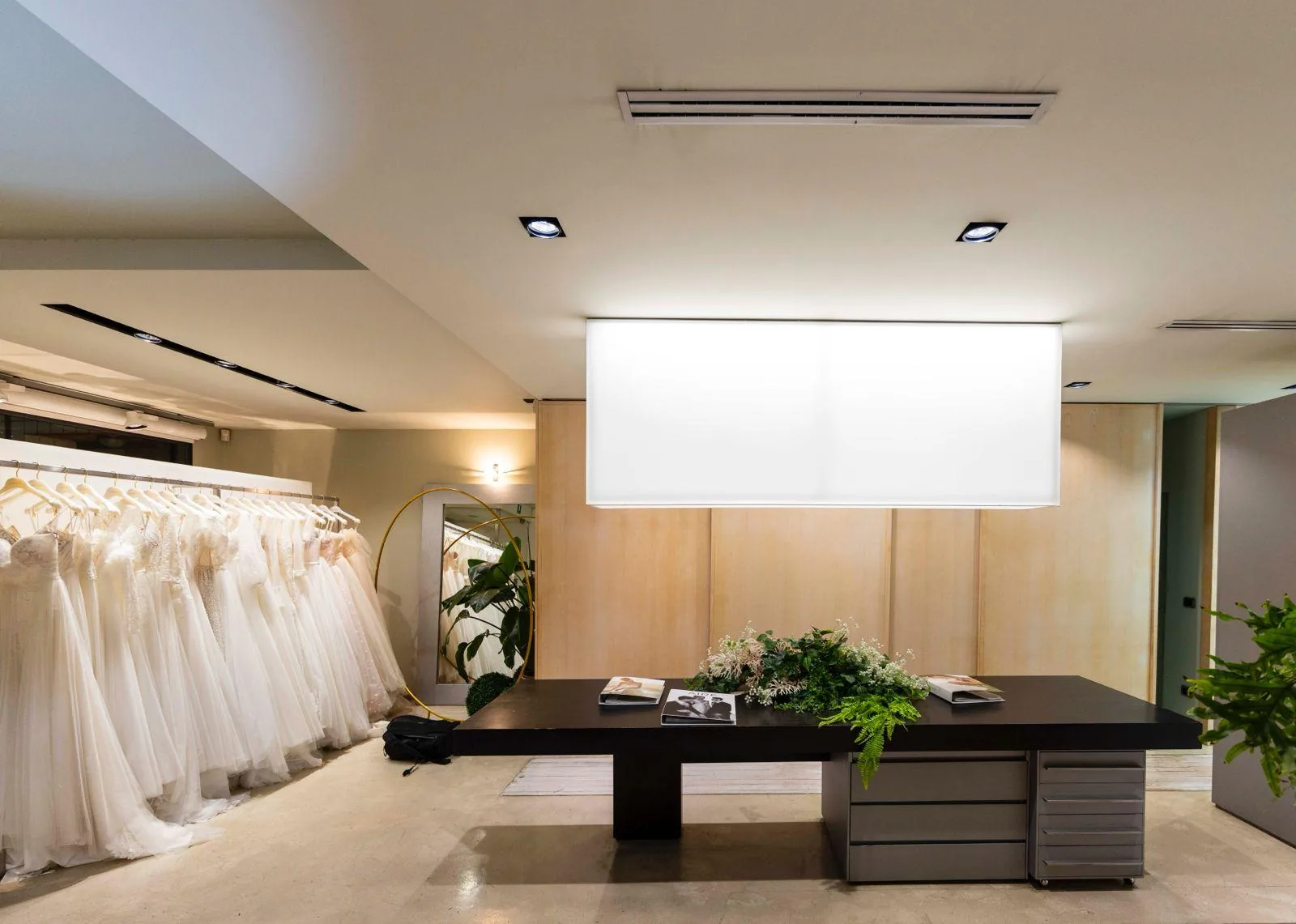 Abiti da sposa esposti accanto al tavolo centrale dell’atelier.